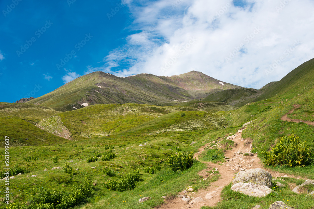 Kazbegi, Georgia - Jun 29 2018: Mountain range on a hiking trail from Gergeti Trinity Church to Gergeti Glacier. a famous landscape in Kazbegi, Mtskheta-Mtianeti, Georgia. Kazbegi, Georgia - Jun 29 2018: Mountain range on a hiking trail from Gergeti Trinity Church to Gergeti Glacier. a famous landscape in Kazbegi, Mtskheta-Mtianeti, Georgia.