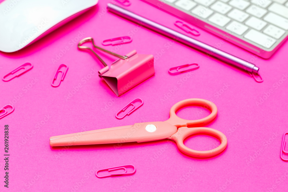 Desktop and pink paper clips, scissors on plastic pink background