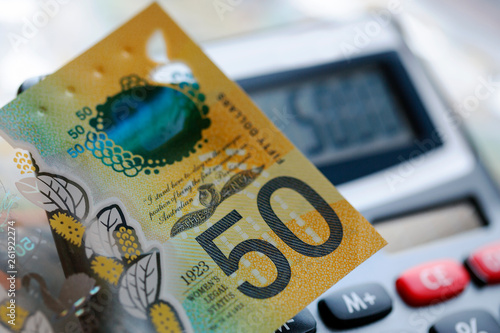 Australian fifty dollar bill over a calculator. The new 2019 issue is designed to deter counterfeiting, the note is polymer and water resistant with a clear holographic strip photo