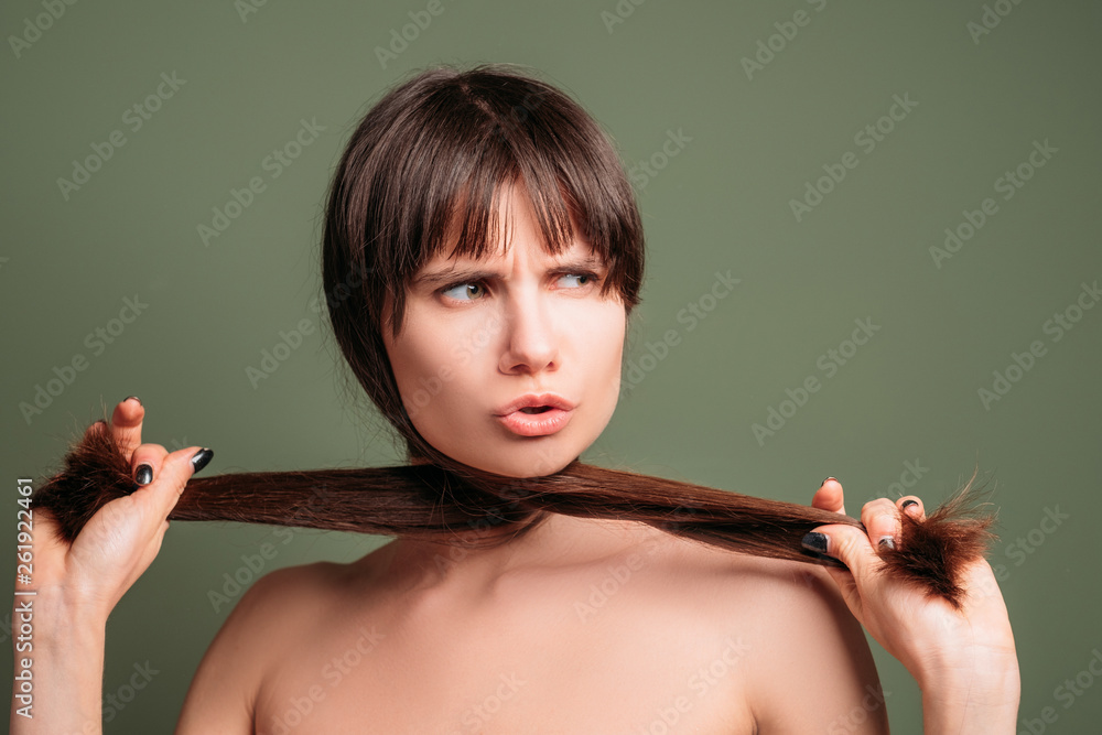 Obraz premium Aggressive pretty woman. Hostile facial expression. Closeup portrait of emotional lady pulling aside hair, crossed under her chin.