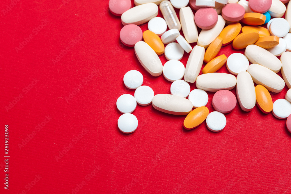 Multicolored pills on red background. Medical concept. Texture. Multicolored pills on red background. Medical concept. Texture.