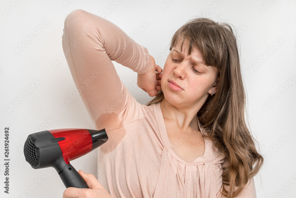 Woman is drying her sweating armpit with hair dryer Woman is drying her sweating armpit with hair dryer