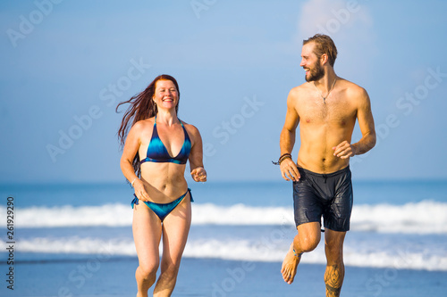 beautiful couple enjoying Summer holidays travel or honeymoon trip together in tropical paradise beach having fun running carefree and playful on the sea