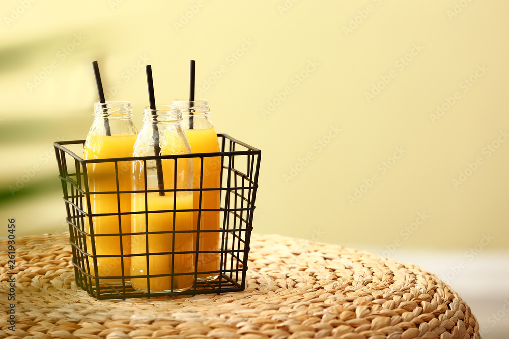 Basket with bottles of tasty orange juice on wicker table Basket with bottles of tasty orange juice on wicker table