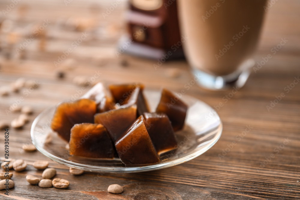 Plate with iced coffee cubes on wooden table Plate with iced coffee cubes on wooden table