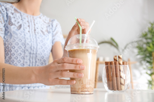 Woman drinking tasty frappe coffee at table