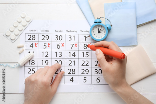 Woman marking her period in menstrual calendar