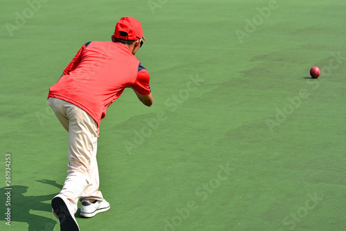 Man in red shirt playing lawn bowl