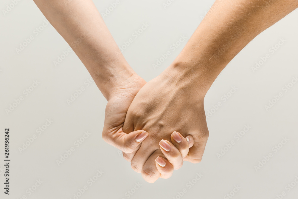 Leading you on. loseup shot of male and female holding hands isolated on grey studio background. Concept of human relations, friendship, partnership, family. Copyspace. Leading you on. loseup shot of male and female holding hands isolated on grey studio background. Concept of human relations, friendship, partnership, family. Copyspace.