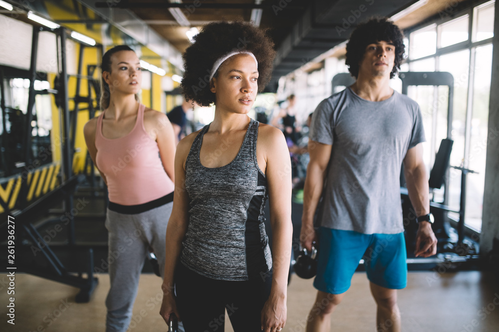Naklejka premium Group of young people doing exercises in fitness club