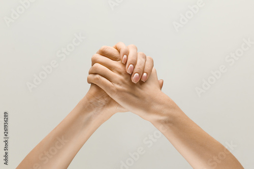 Win together. loseup shot of male and female holding hands isolated on grey studio background. Concept of human relations, friendship, partnership, family. Copyspace.