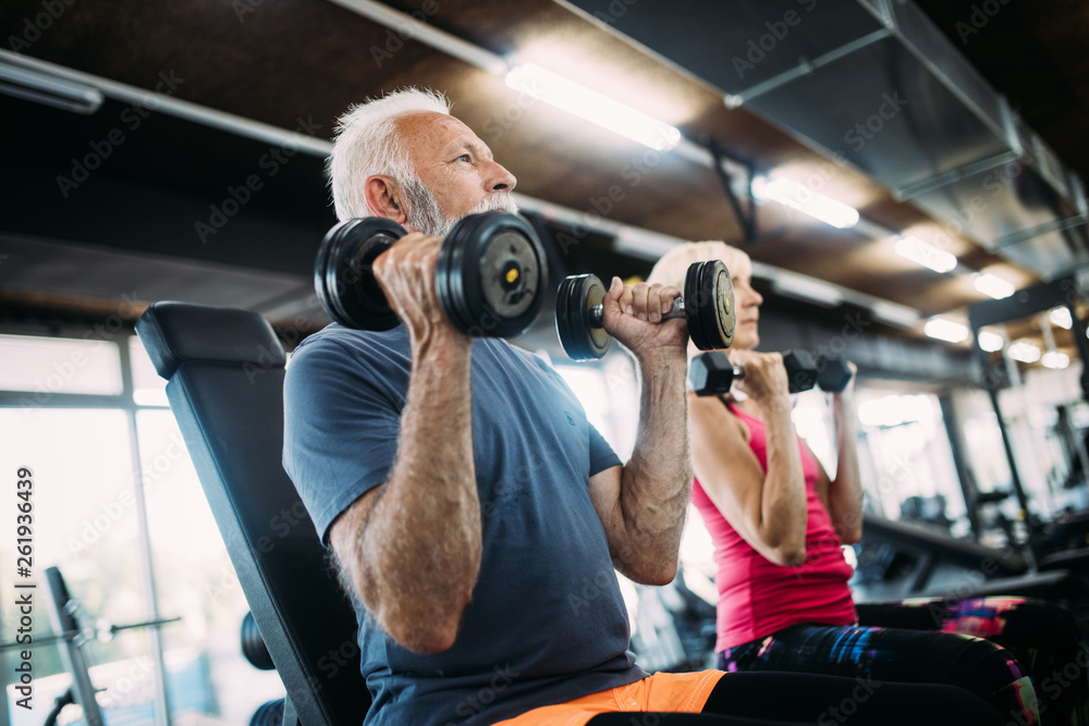 Mature fit couple exercising in gym to stay healthy Mature fit couple exercising in gym to stay healthy