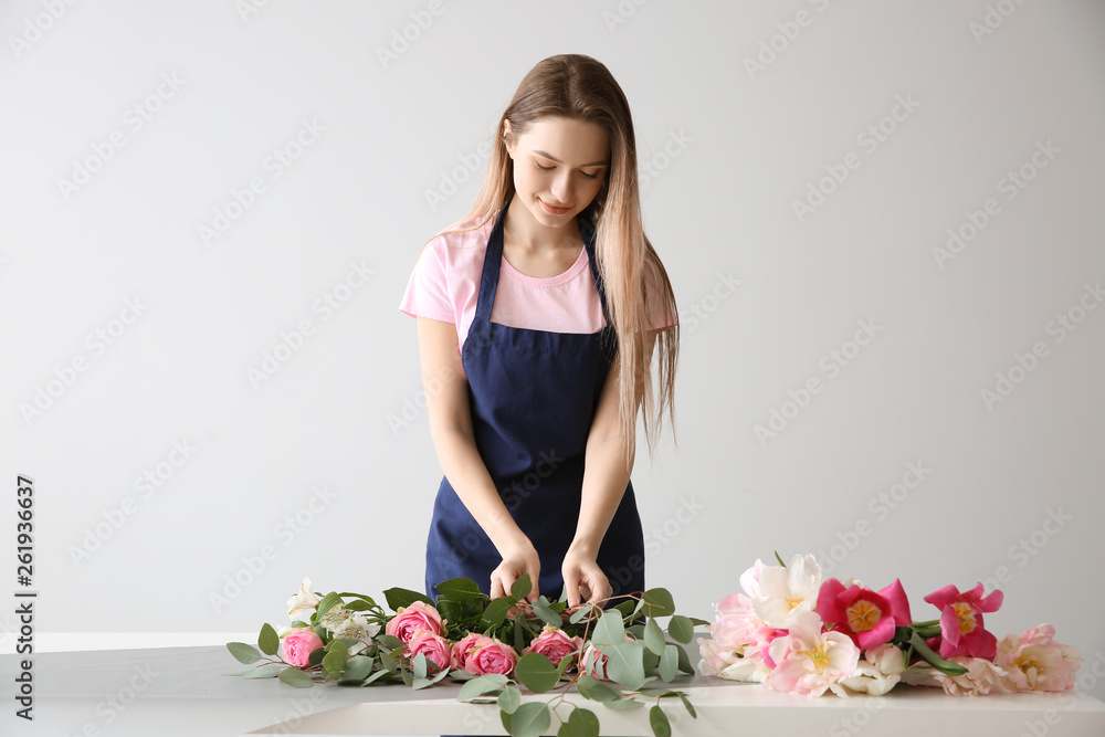 Florist making bouquet at table against light background Stock Photo