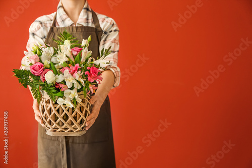 Florist holding beautiful bouquet on color background