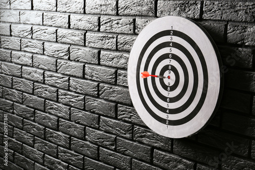 Dartboard with hit bullseye on dark brick wall photo