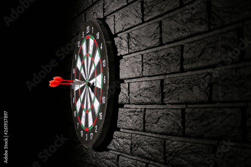 Dartboard with hit bullseye on dark brick wall photo