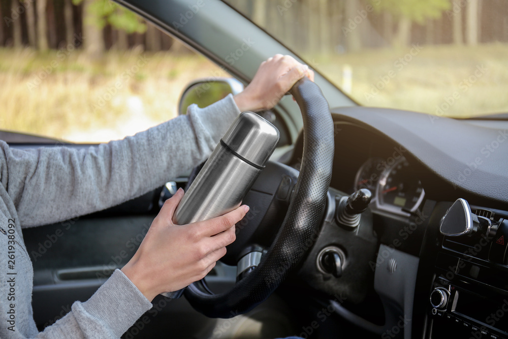 Woman with thermos driving a car Woman with thermos driving a car