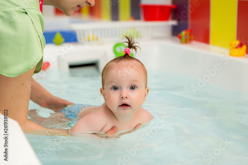 infant swimming,Mother teaching baby to swim in water pool,Little baby's first swim 