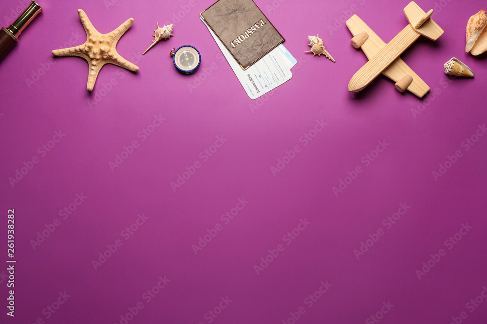 Toy airplane with passport, tickets, compass and seashells on color