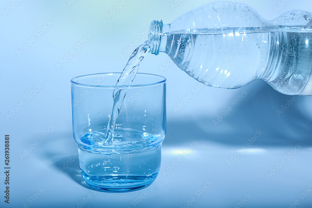 Pouring of water into glass on color background Pouring of water into glass on color background