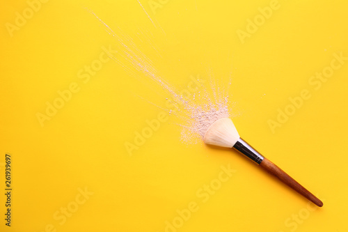 Facial powder and brush on color background