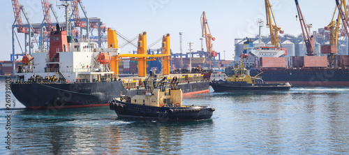 Tugboat assisting Cargo Ship maneuvered into the Port of Odessa, Ukraine. Handling of goods and the work of a commercial port.