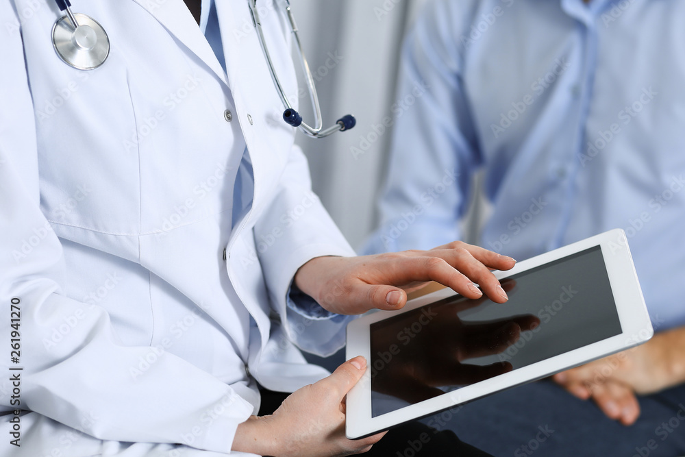 Female doctor using touchpad or tablet computer while consulting man patient in hospital. Medicine and healthcare concept Female doctor using touchpad or tablet computer while consulting man patient in hospital. Medicine and healthcare concept