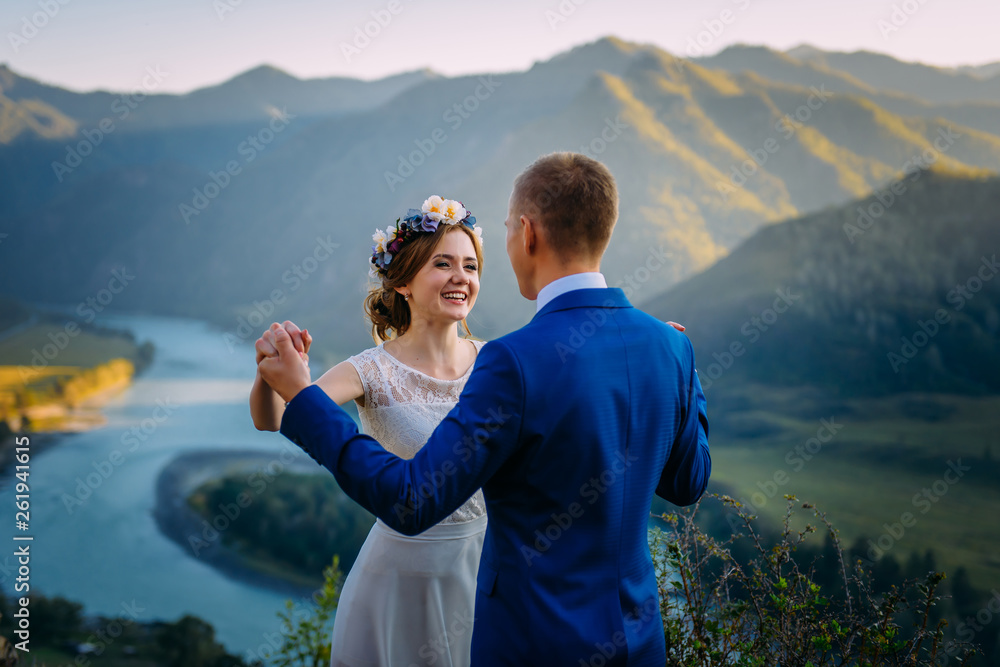 Happy wedding couple staying over the beautiful landscape with mountains