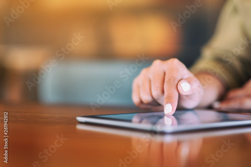 Closeup image of a woman pointing finger at tablet pc on wooden table