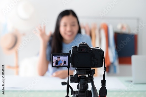 Asian beautiful women blogger are using the camera live streaming online in the shop with clothing products on clothes rack.Concept of online shopping business.