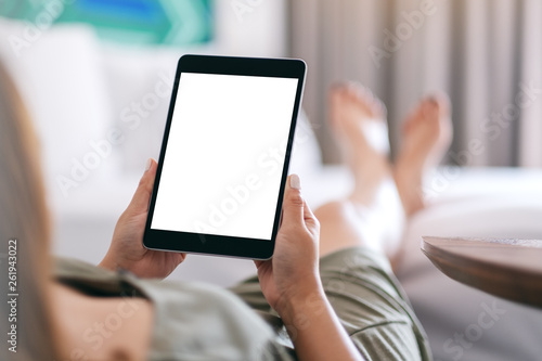 Mockup image of a woman holding and using tablet pc with blank screen while relaxing and lying on the bed © Farknot Architect