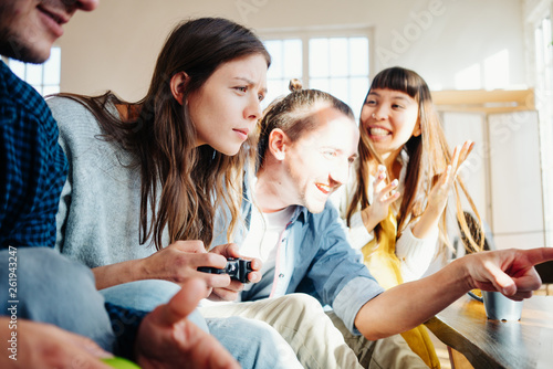 Group of friends playing video games together using controller in big bright apartment