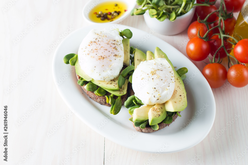 Avocado toast, cherry tomato on wooden background. Breakfast with toast avocado, vegetarian food, healthy diet concept. Healthy sandwich with avocado and poached eggs.
