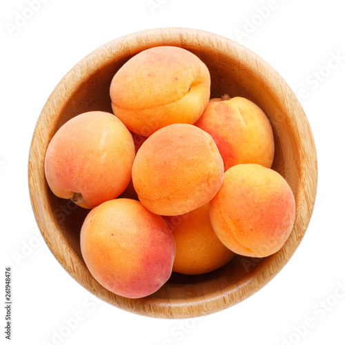 Fresh ripe apricots in wooden bowl isolated on a white background.  Top view, close-up.