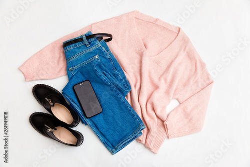 Women's fashion clothing and accessories. Female youth collage on white background top view. A flat lay-out in feminine style looks with a warm sweater, jeans, shoes. Top view. 