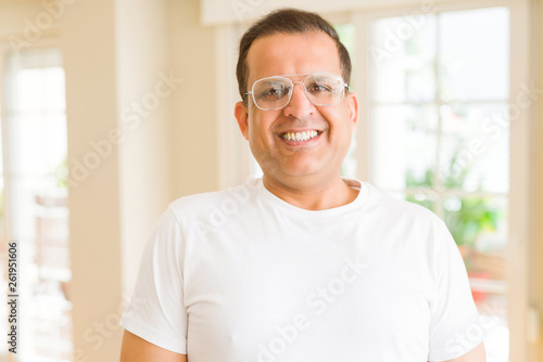 Middle age man wearing glasses smiling to the camera at home