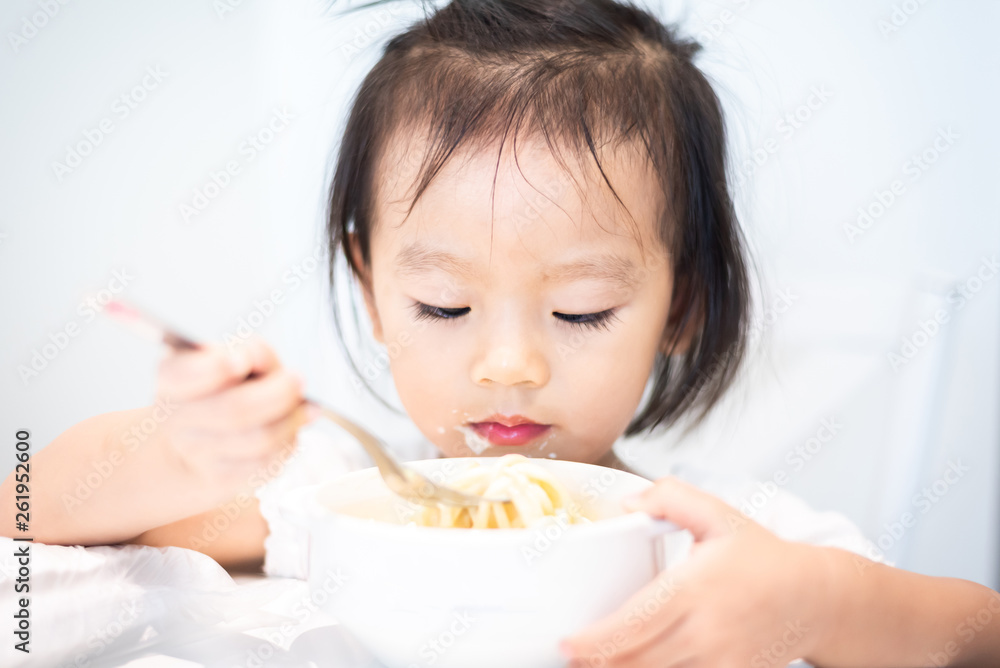 Asian little baby child eating noodle and enjoy breakfast by herself Asian little baby child eating noodle and enjoy breakfast by herself