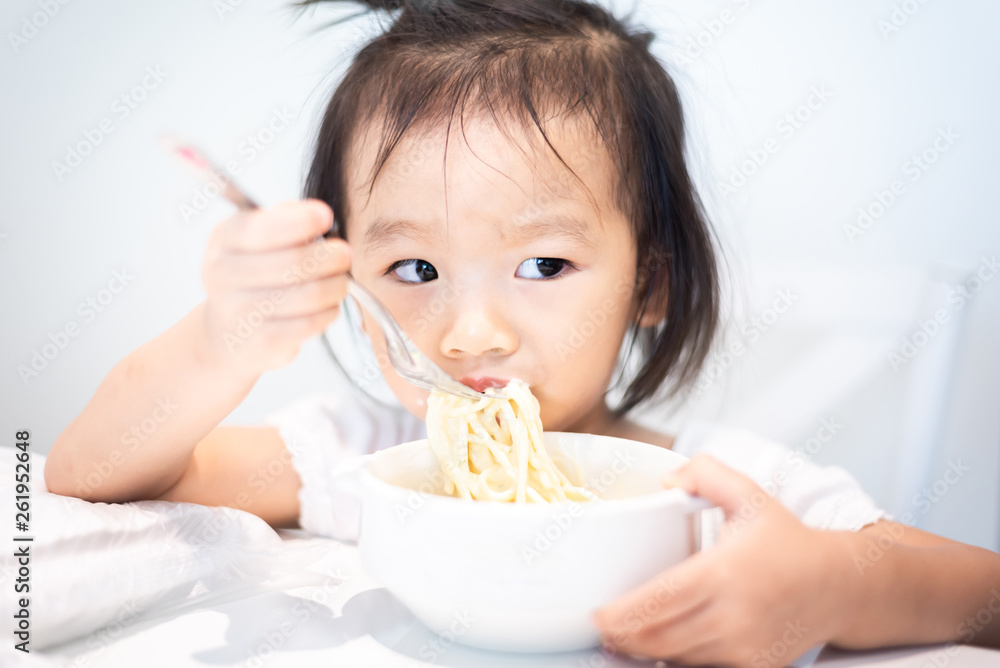 Asian little baby child eating noodle and enjoy breakfast by herself Asian little baby child eating noodle and enjoy breakfast by herself