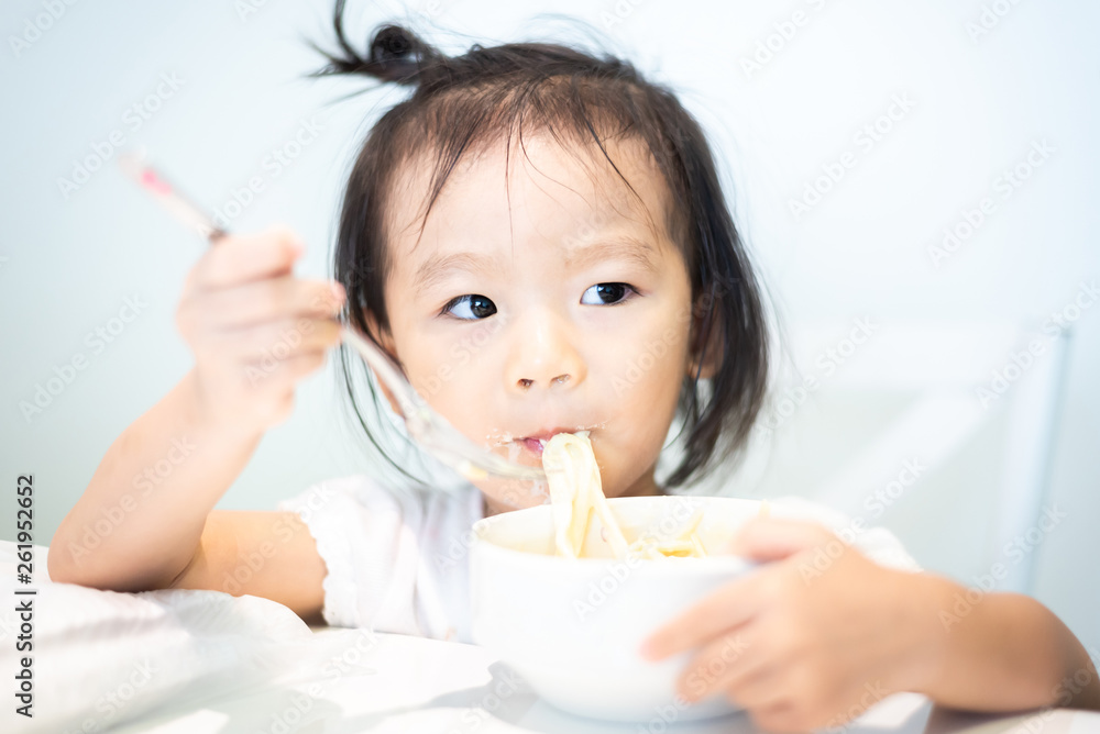 Asian little baby child eating noodle and enjoy breakfast by herself Asian little baby child eating noodle and enjoy breakfast by herself