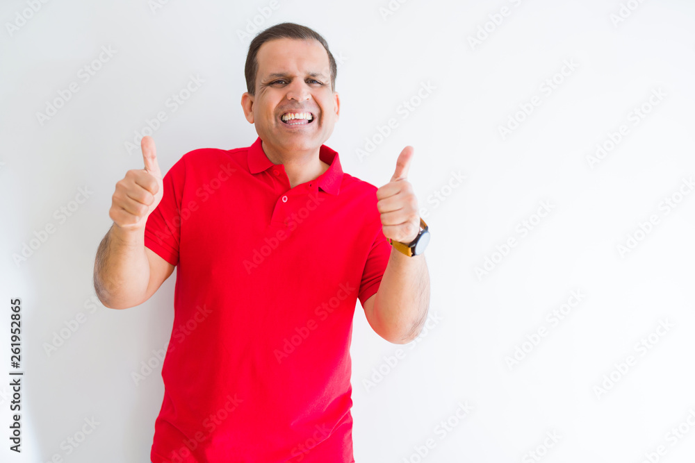 Middle age man wearing red t-shirt over white wall success sign doing positive gesture with hand, thumbs up smiling and happy. Looking at the camera with cheerful expression, winner gesture. Middle age man wearing red t-shirt over white wall success sign doing positive gesture with hand, thumbs up smiling and happy. Looking at the camera with cheerful expression, winner gesture.