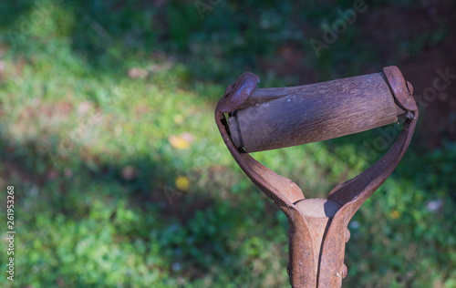 Damaged rusted handle of a retro garden tool isolated against a green background image with copy space photo