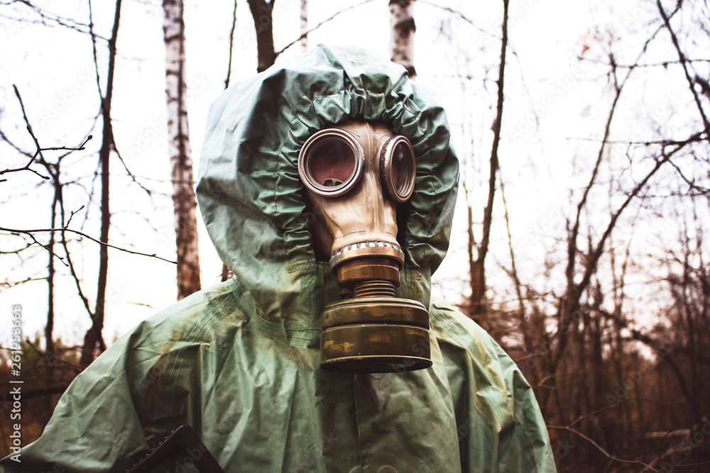 Stalker, a man in a gas mask and special chemical protection, green cloak.  Portrait in gas mask close up.