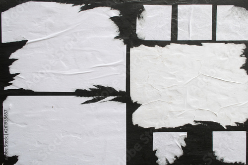 Several sheets of white paper pasted on a black wall. photo