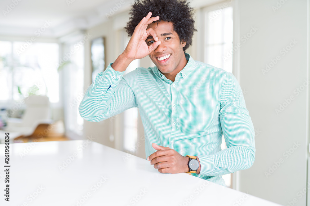 African American business man wearing elegant shirt doing ok gesture with hand smiling, eye looking through fingers with happy face.
