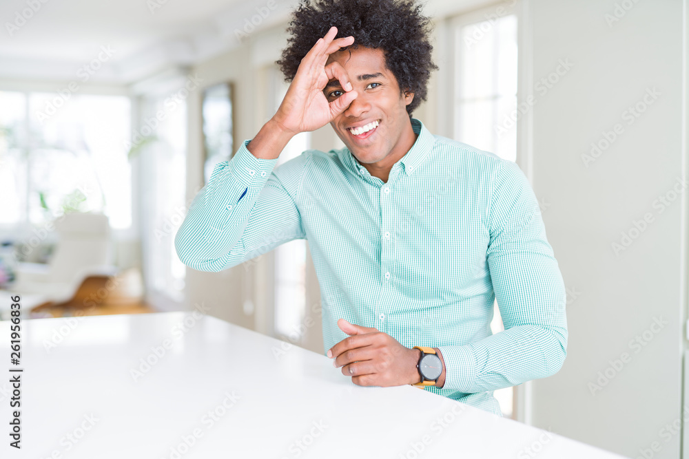 Fototapeta premium African American business man wearing elegant shirt doing ok gesture with hand smiling, eye looking through fingers with happy face.