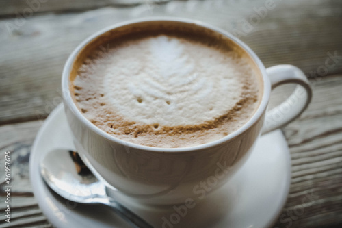 cup of coffee with cream on wooden background