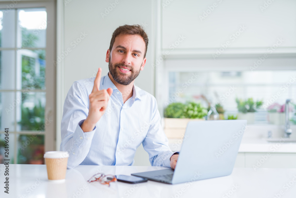 Handsome man working using computer laptop and drinking a cup of coffee very happy pointing with hand and finger to the side Handsome man working using computer laptop and drinking a cup of coffee very happy pointing with hand and finger to the side