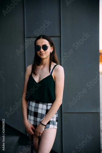 Sexy girl near a dark wall in a T-shirt  sunglasses and short shorts