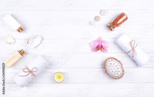 Different spa, beauty and wellness products: cream, balsam, sea salt in glass bottles, towels, massage brush, decorated with flowers, stones, sea shell .