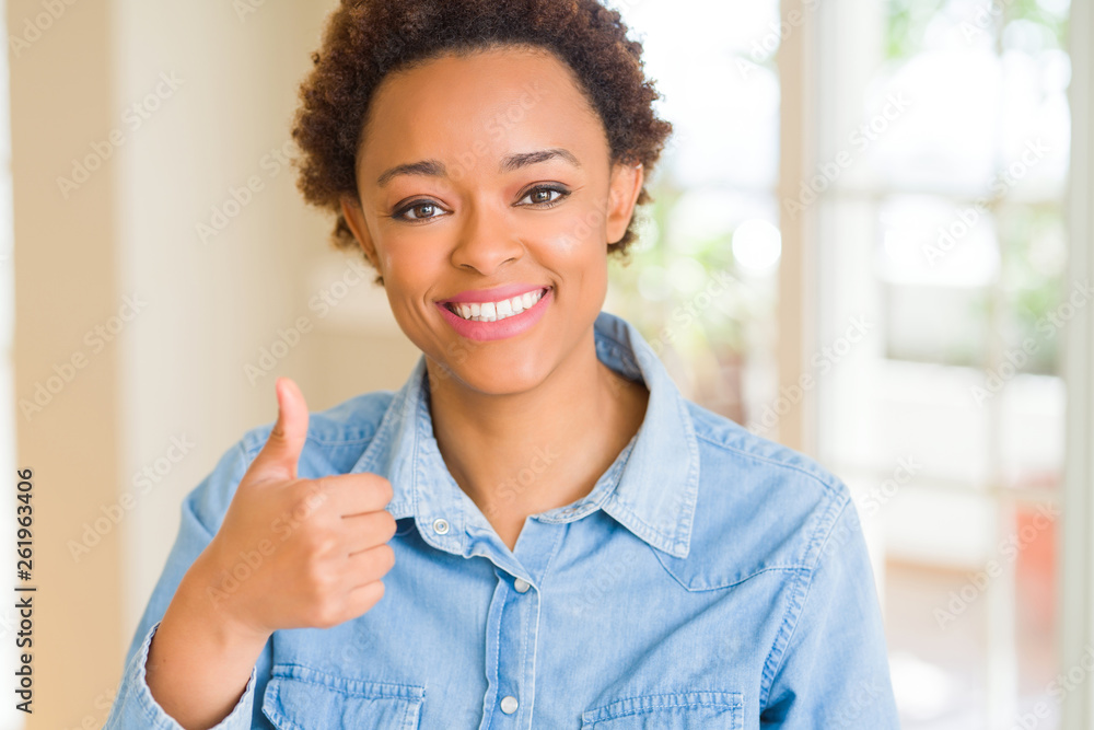 Young beautiful african american woman doing happy thumbs up gesture with hand. Approving expression looking at the camera with showing success.